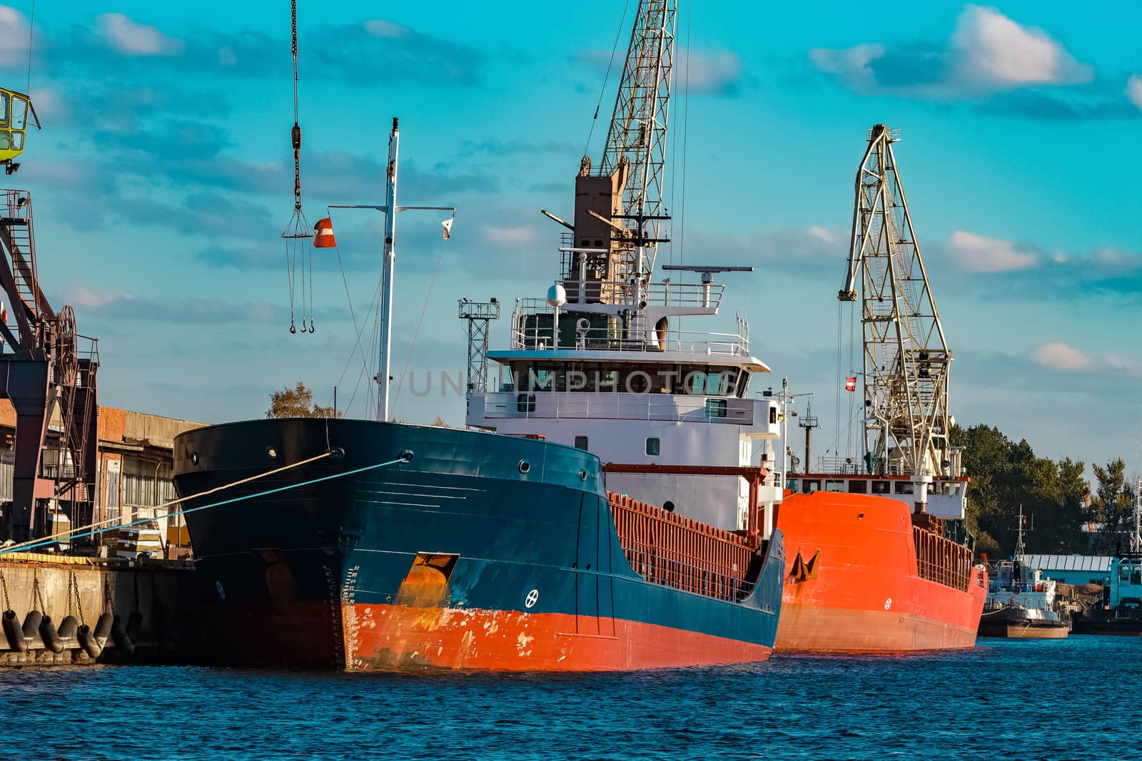 Blue cargo ship moored and loading at the port