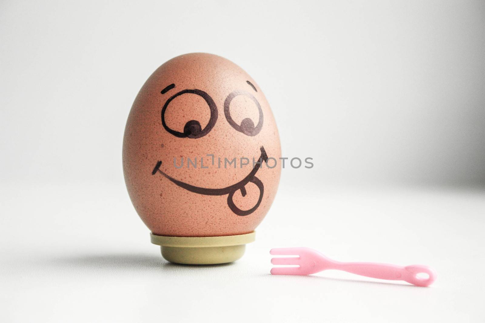 Diet concept. A fork and an egg with a painted brown face. Photo for your design