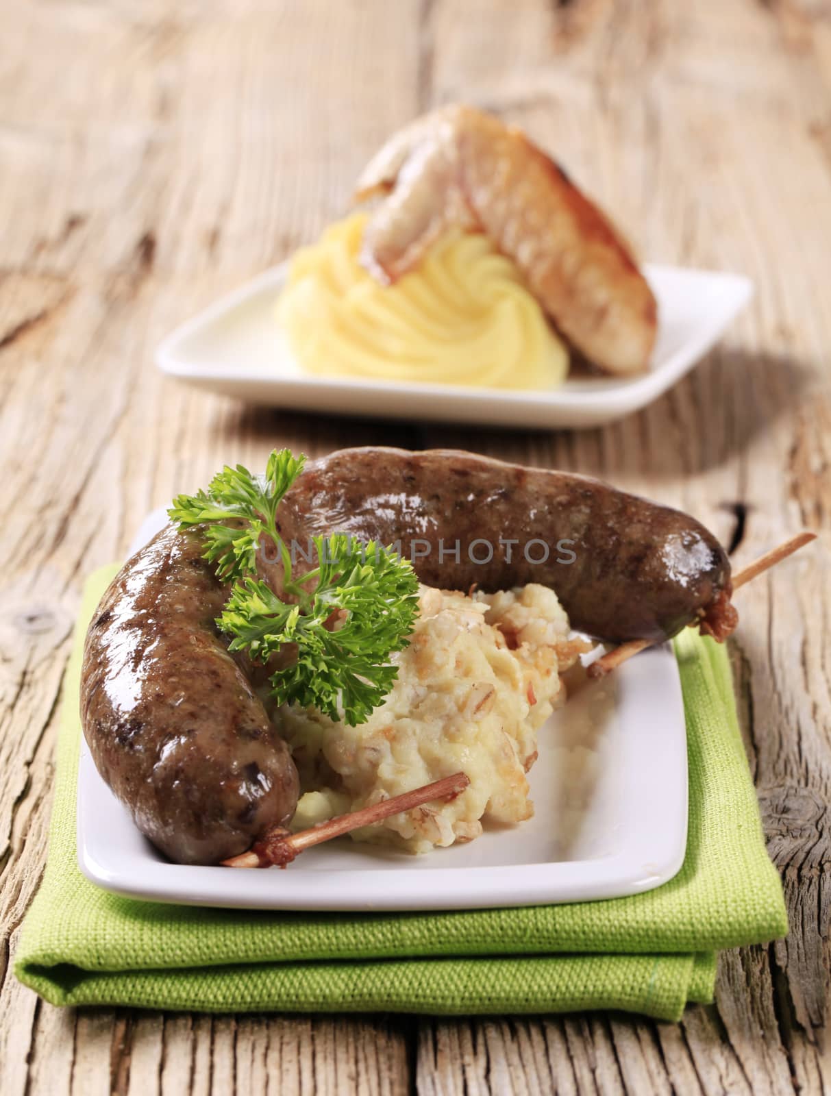 White pudding and mashed potato with peeled barley on wooden background