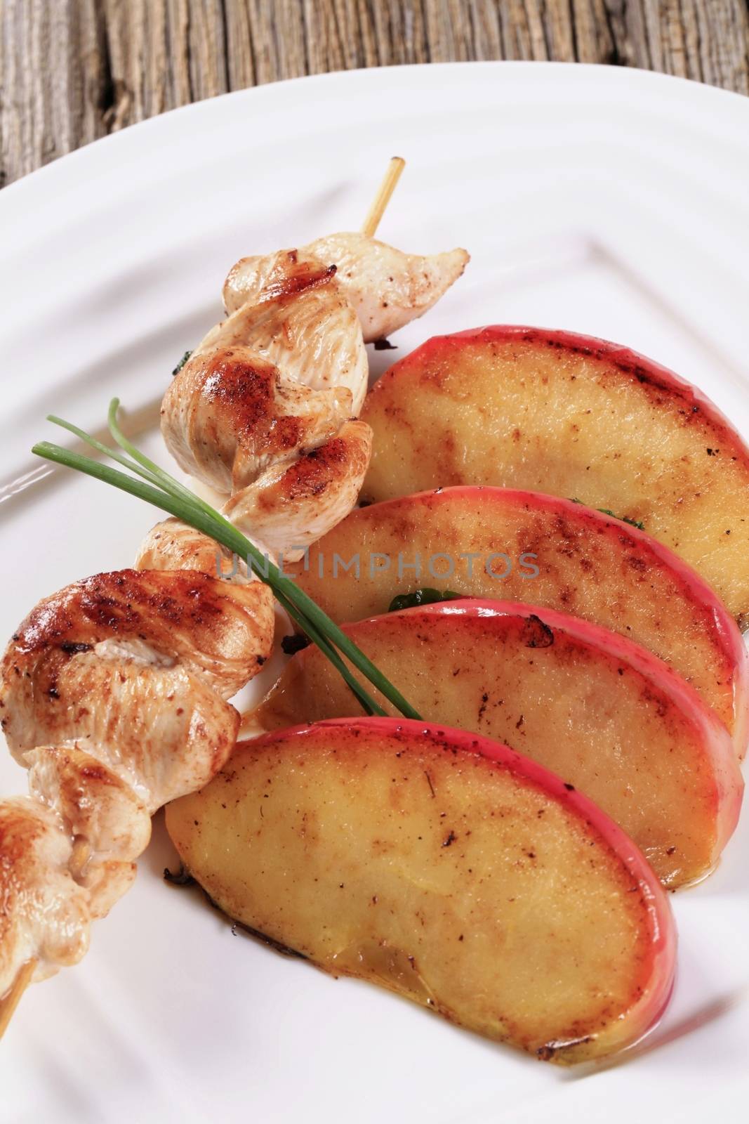 Chicken skewer and slices of baked apple