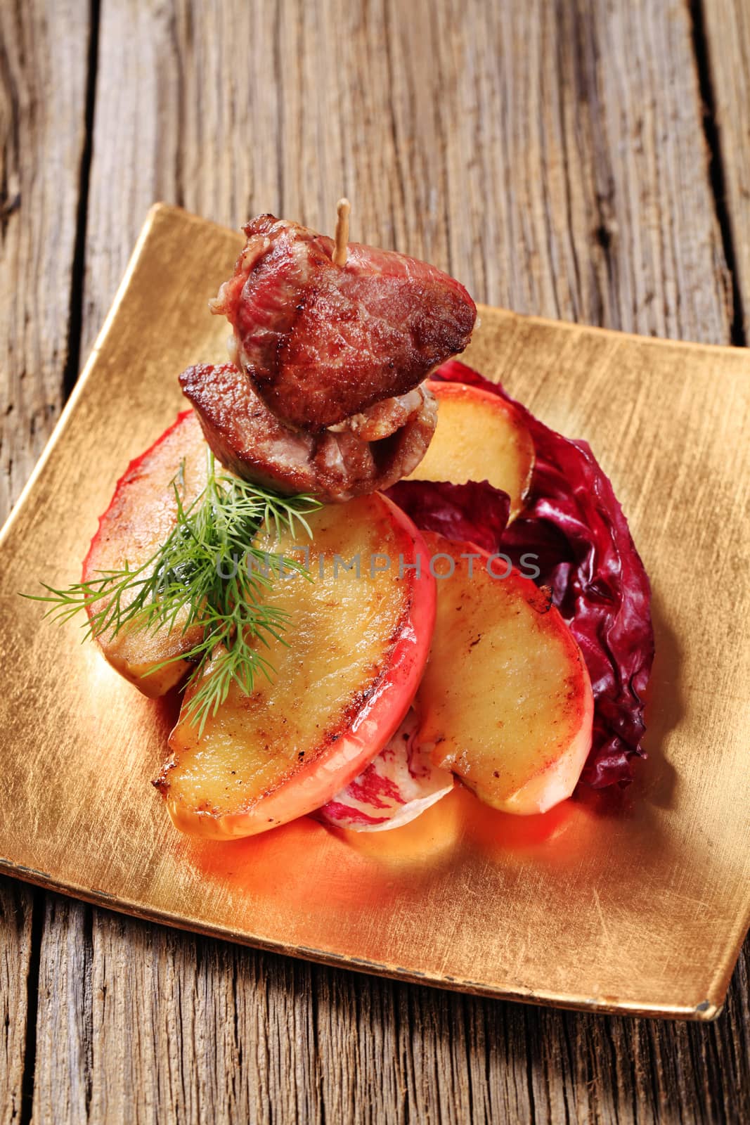 Roasted meat on stick and slices of apple