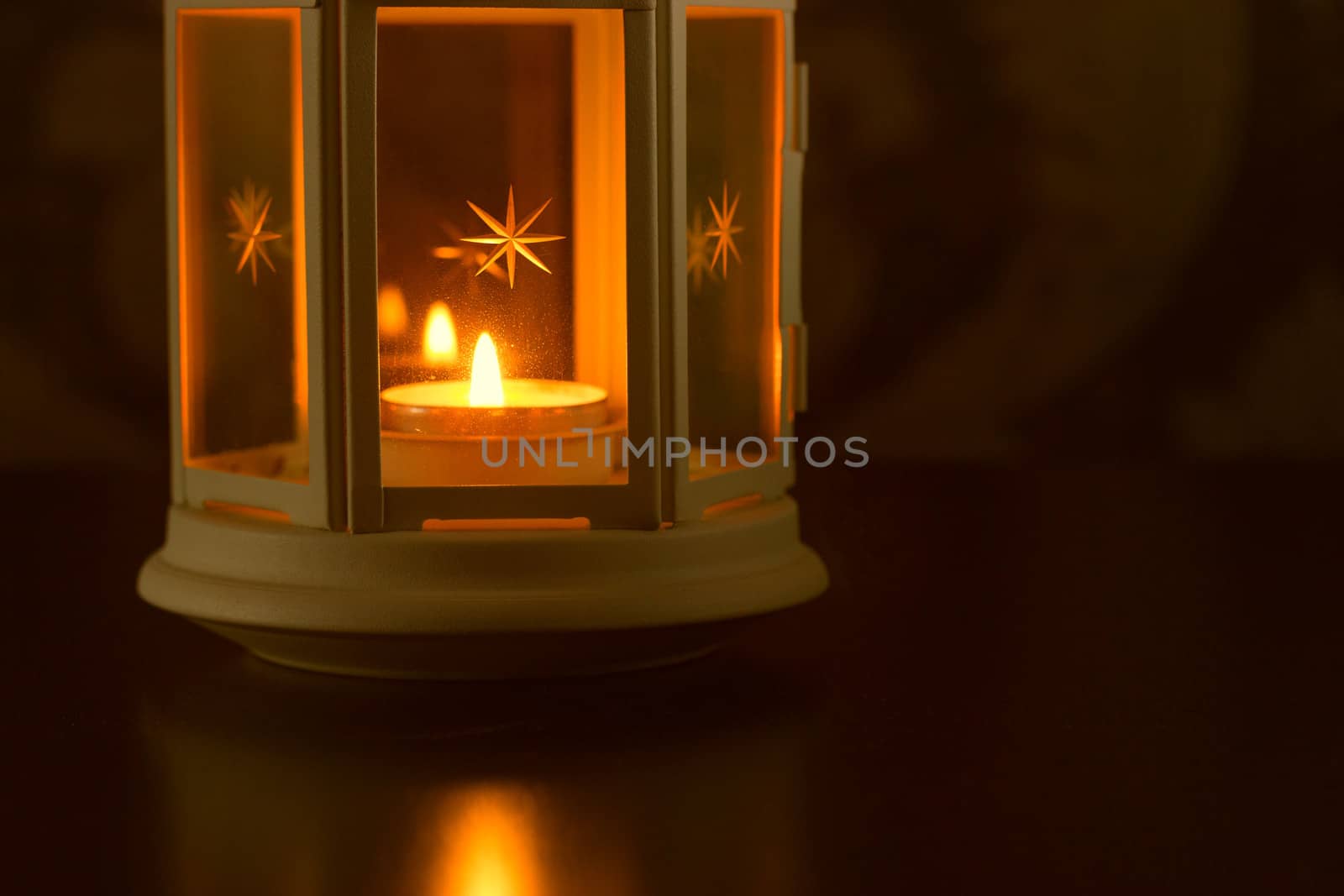 White candle on a white plate standing on a blue wallpaper background