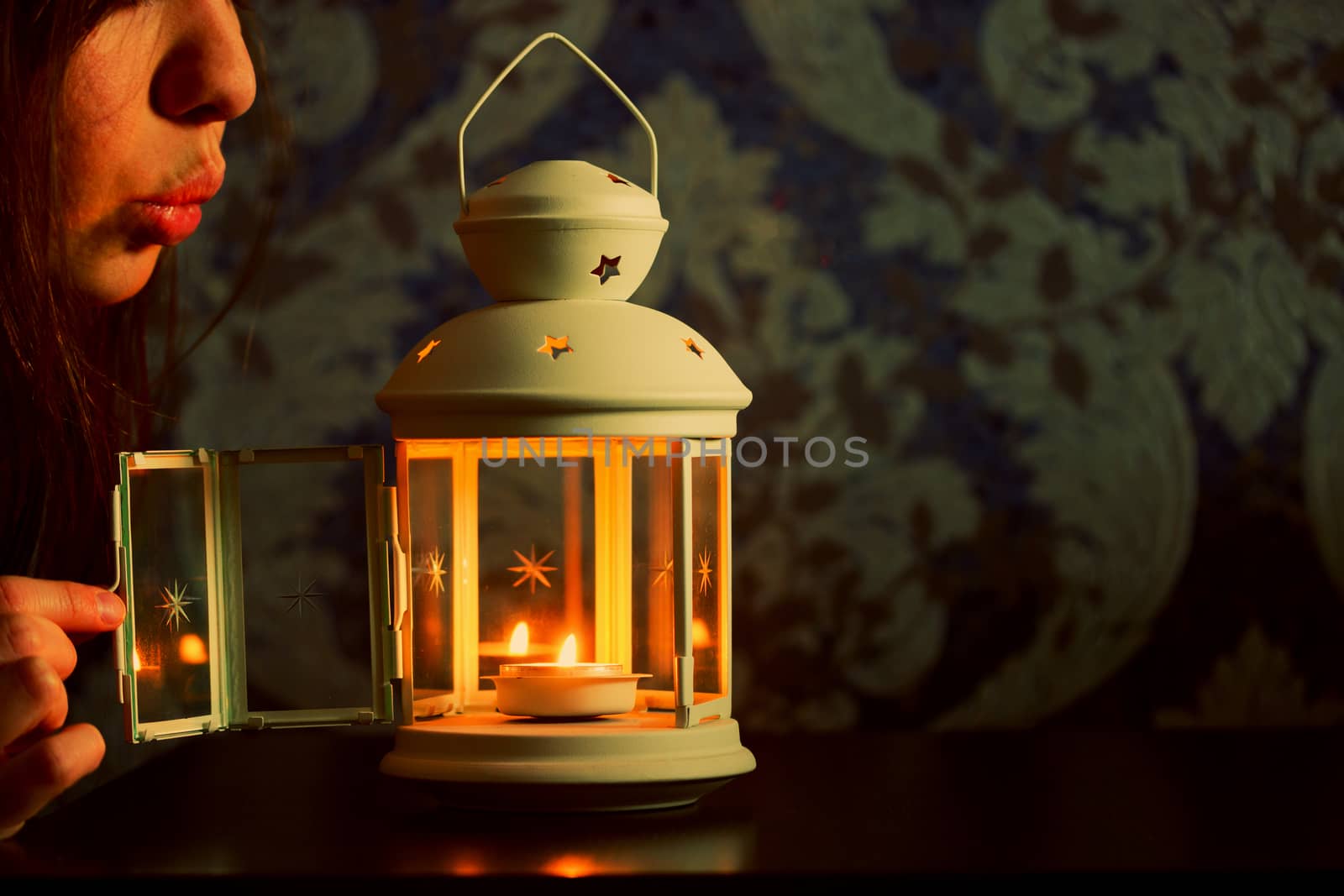 girl blow out a candle in a lantern