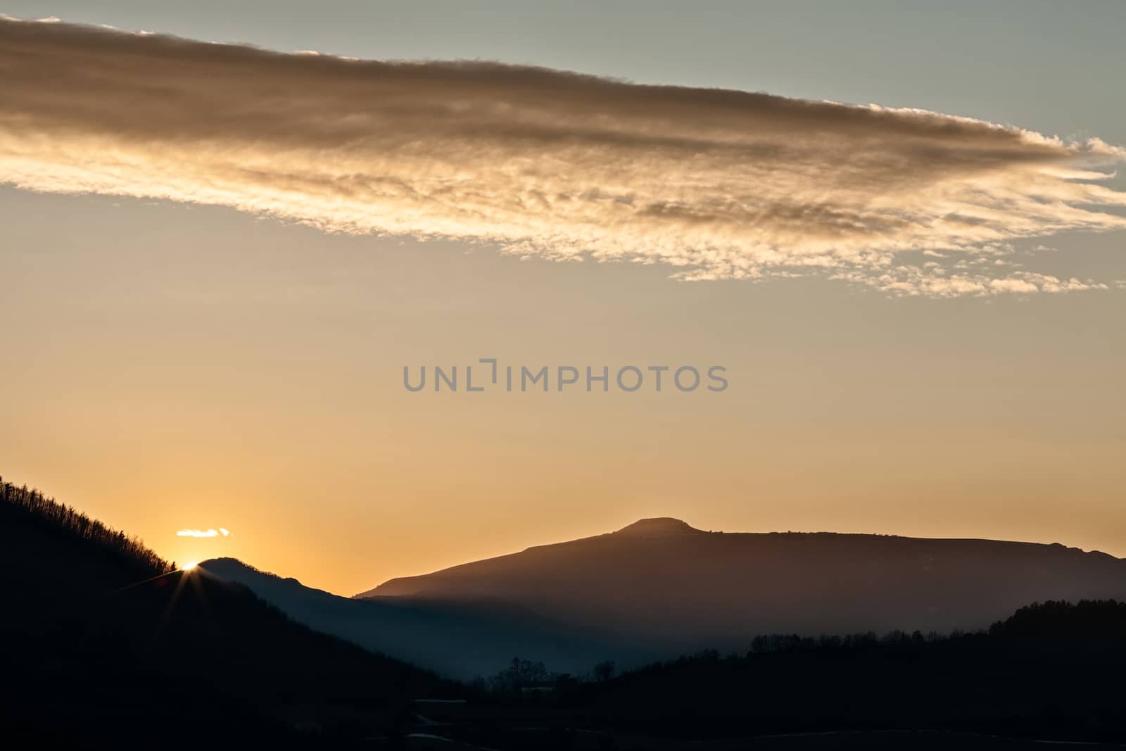 Sunset in the mountain landscape with sunny beams and golden sky