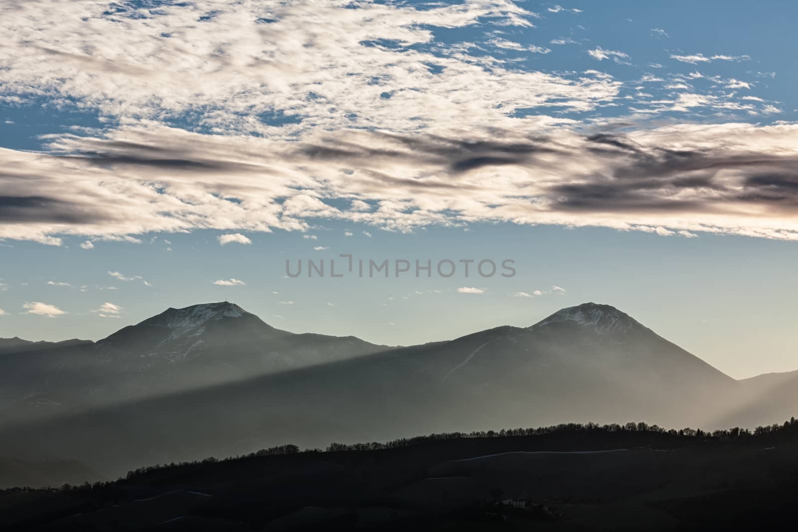 Sunset in the mountains with sunny beams and cloudy sky