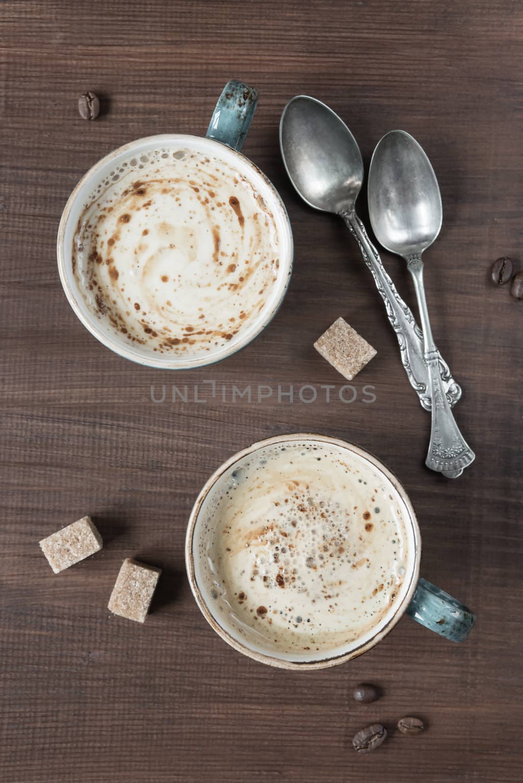 Two cups of coffee and are several pieces of sugar and teaspoons; top view, flat lay