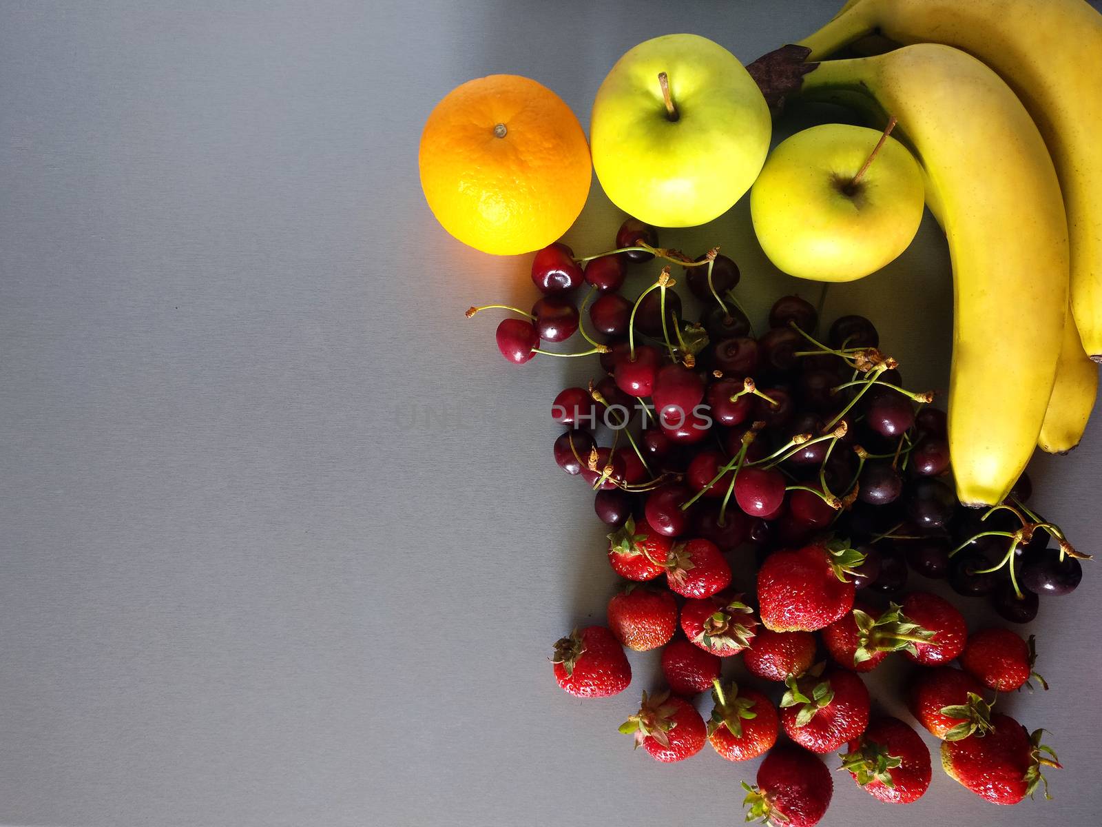 Banana, strawberry, cherry, orange And an apple on a gray background