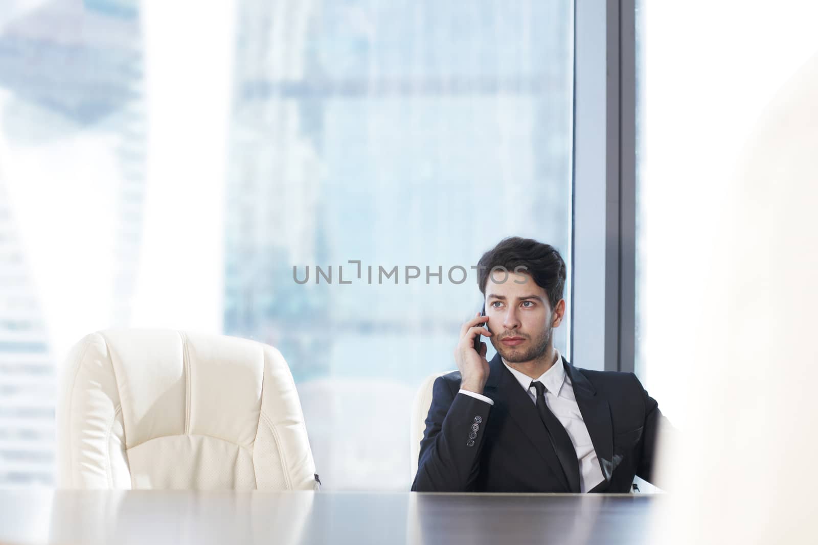 Businessman with cellphone working in office with view at skyscrapers