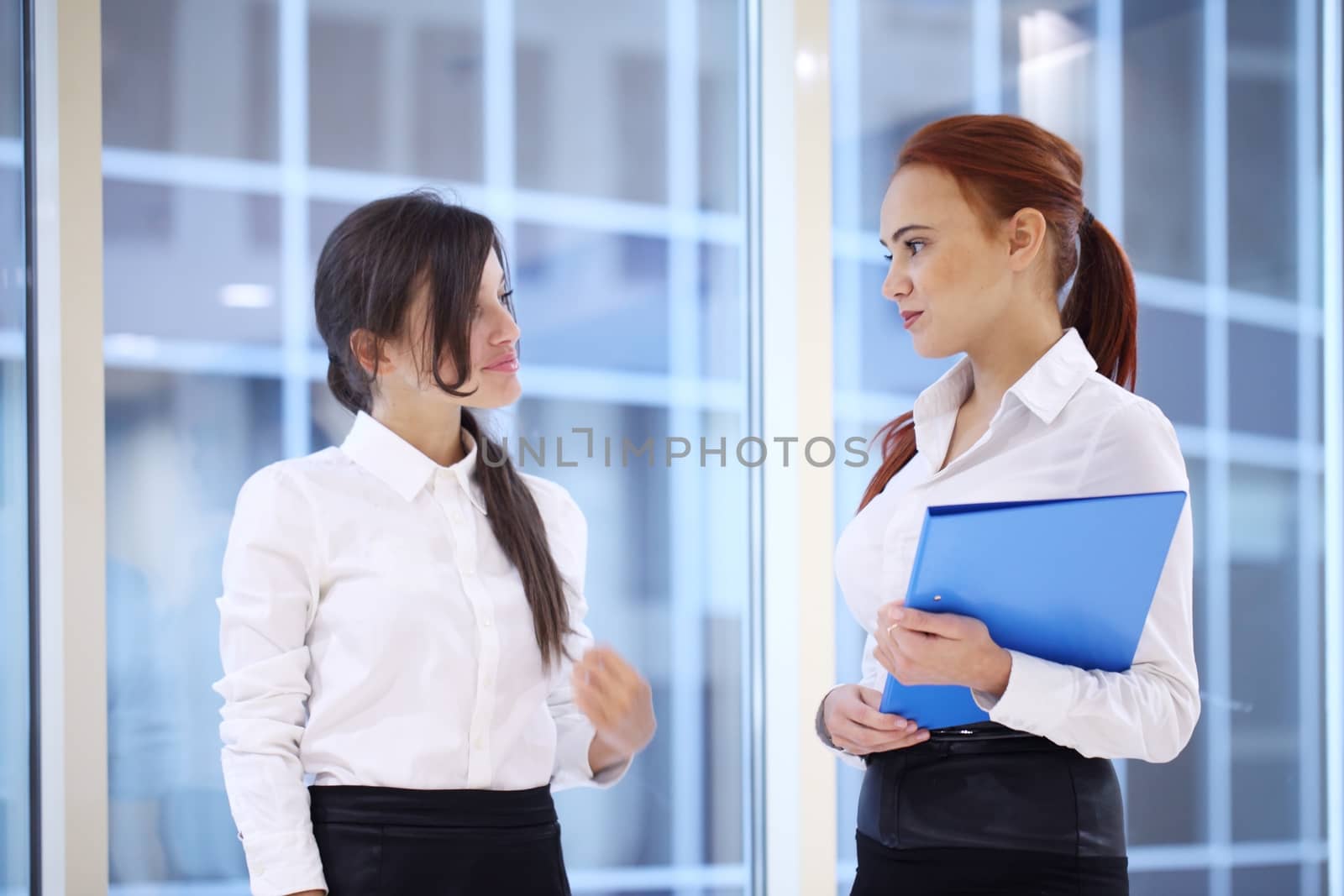 Two young beautiful businesswomen having meeting in modern office