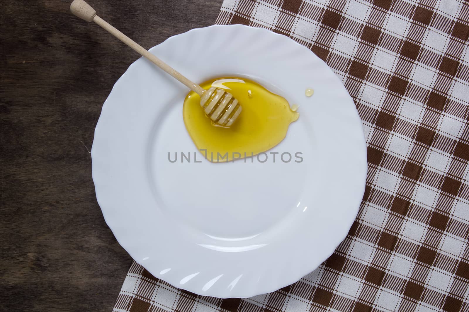 White plate with honey on a wooden table