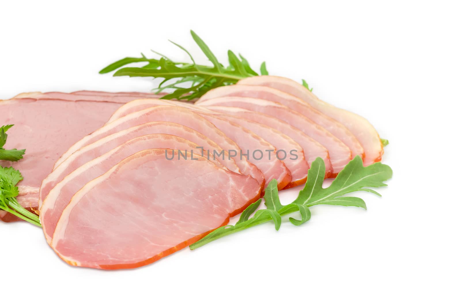 Sliced boiled smoked pork loin and ham with arugula and parsley leaves closeup on a light background
