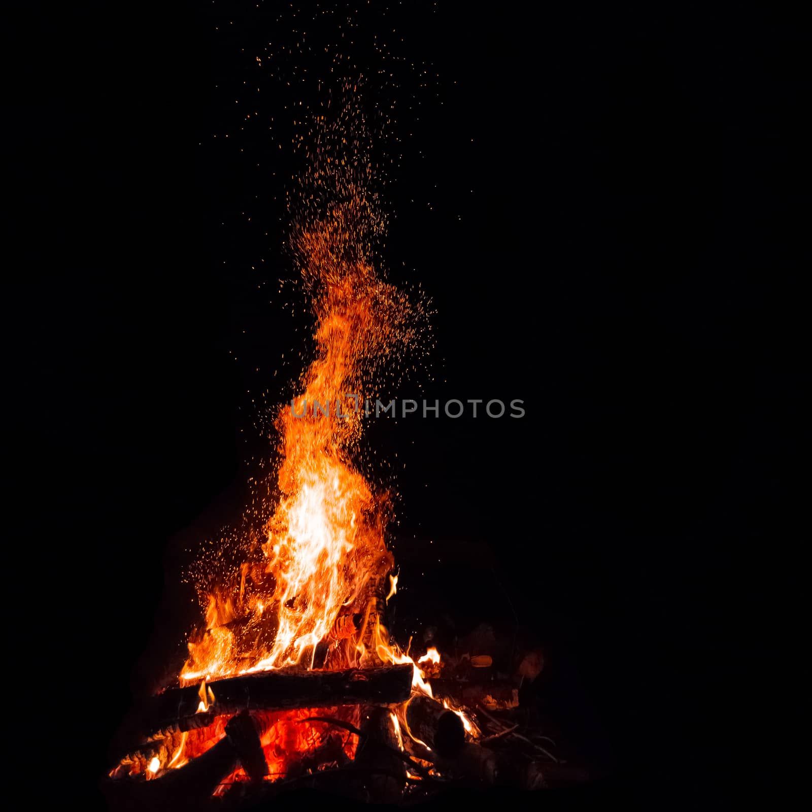 Campfire with flying sparks isolated on black background