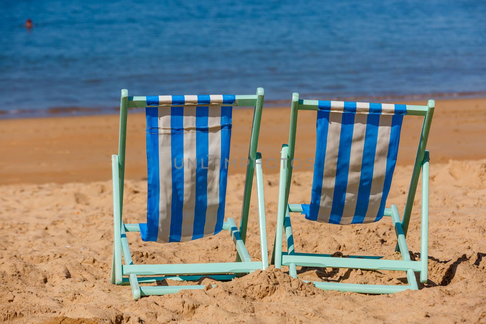 Two empty deckchairs facing the sea by pixinoo