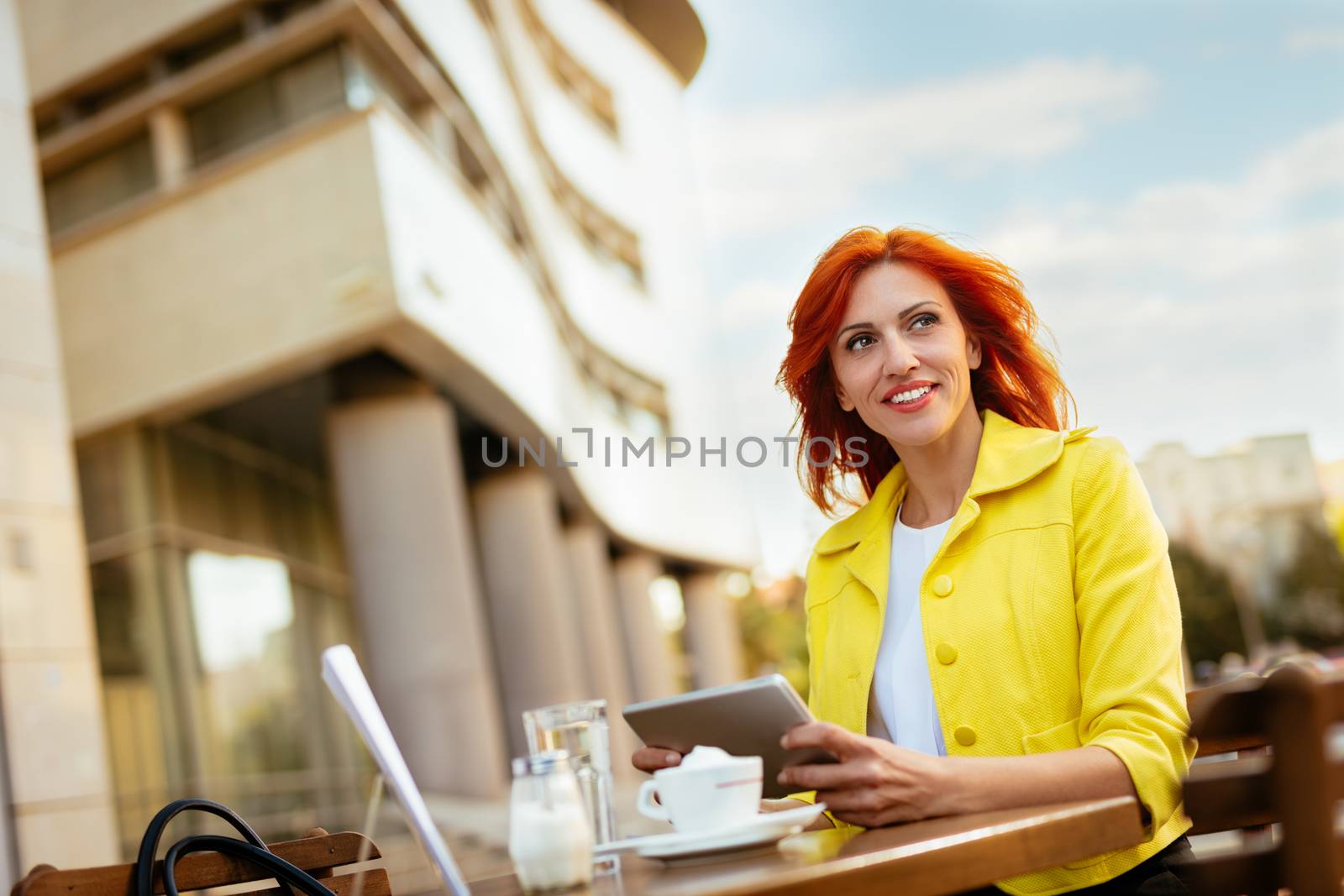 Businesswoman working at the digital tablet on a coffee break in a street cafe.