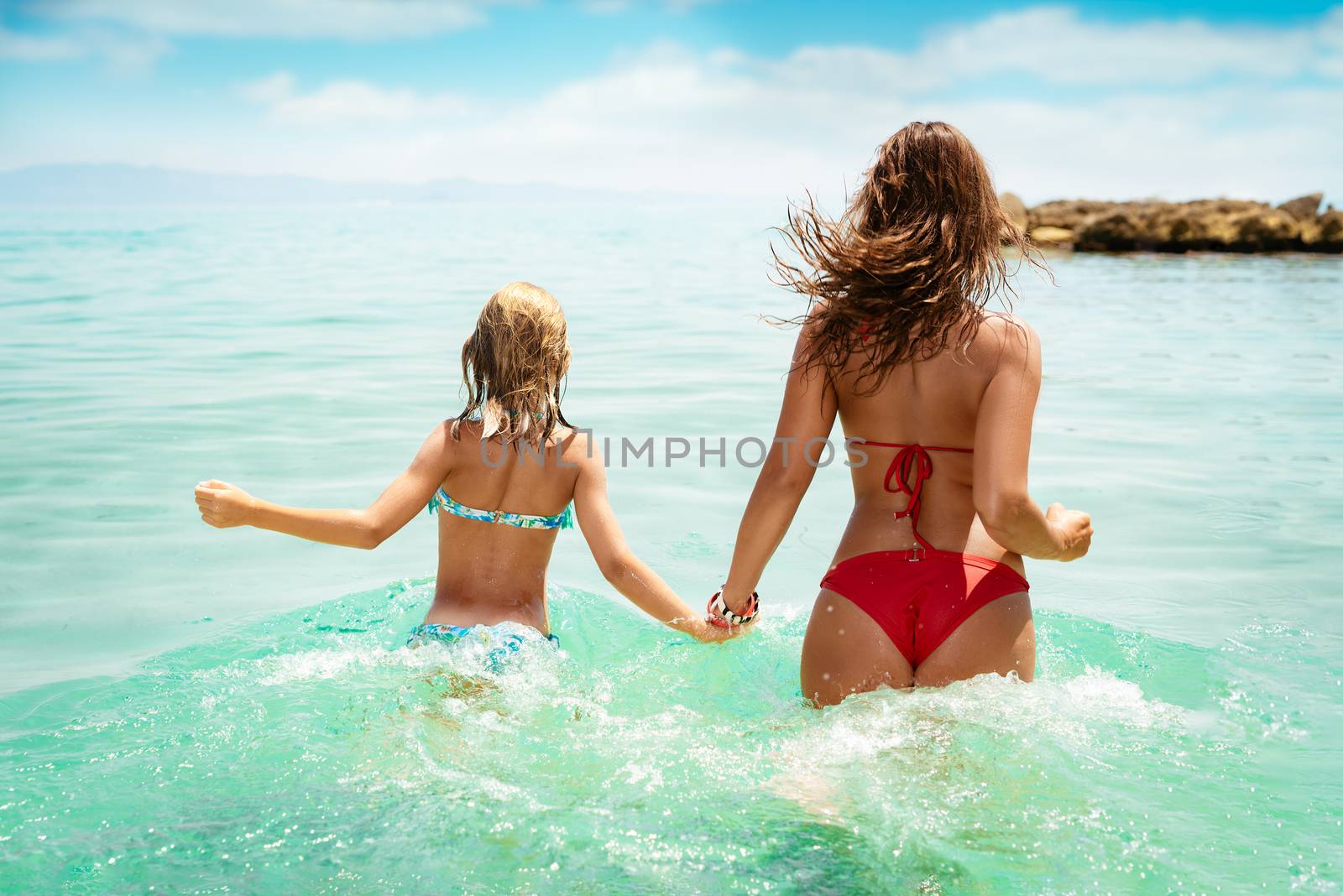 Beautiful little girl enjoying with her mother on the beach. She is having fun in the sea.