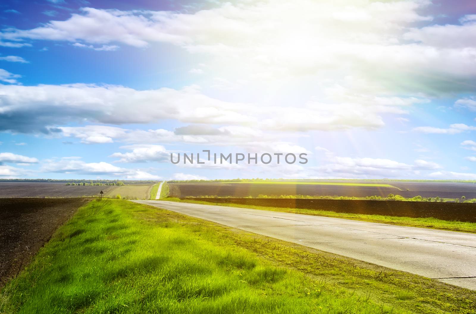 Highway in the hills on a clear sunny day with blue sky and green grass on the roadside
