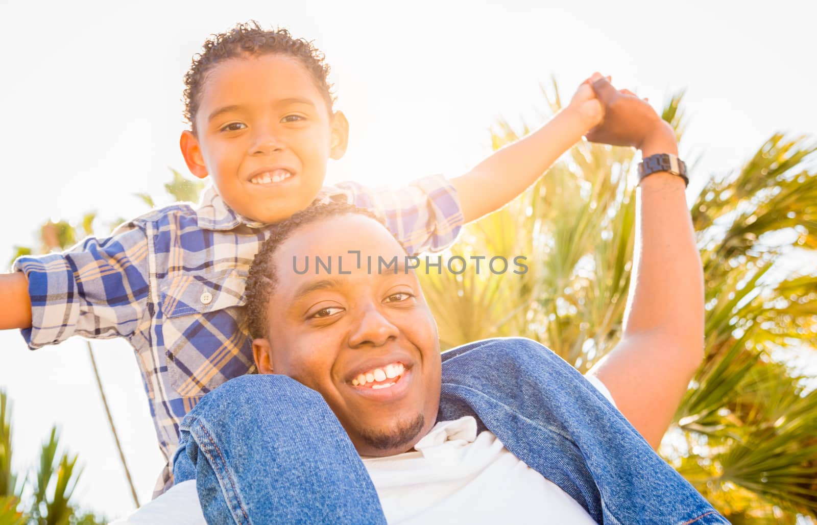 Mixed Race Son and African American Father Playing Piggyback Outdoors Together.