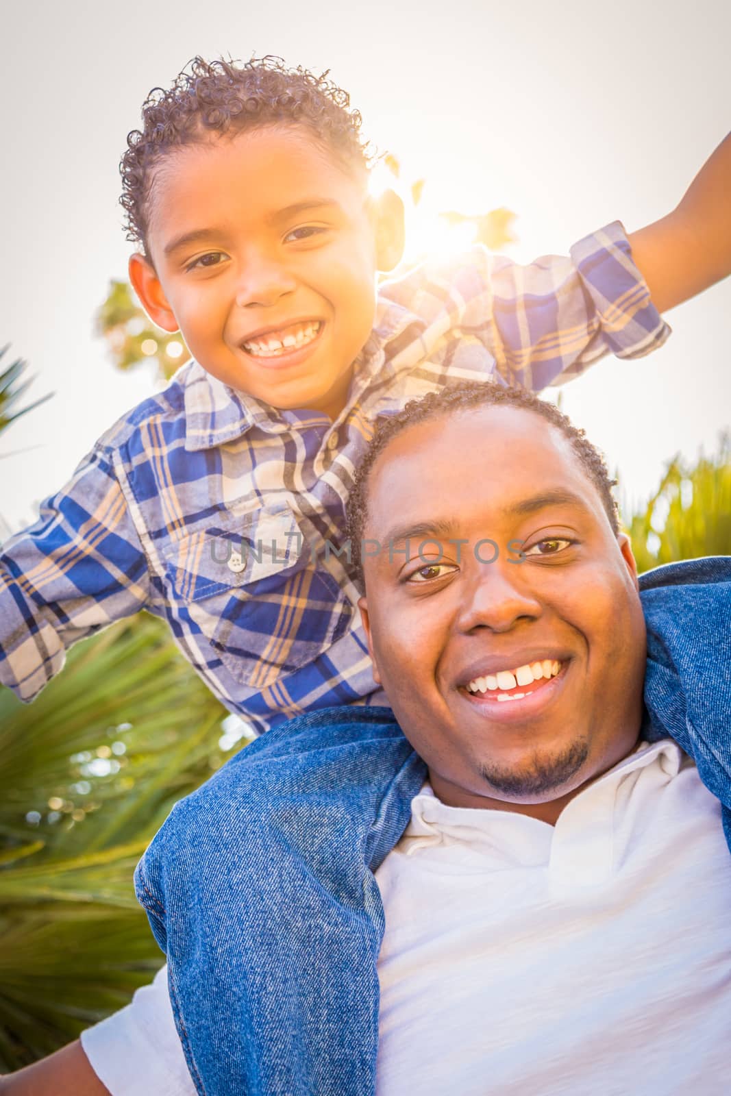 Mixed Race Son and African American Father Playing Piggyback Outdoors Together.