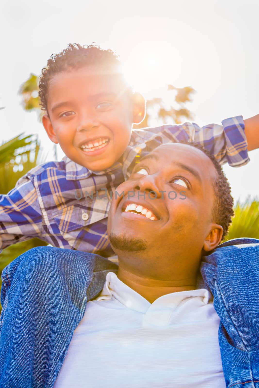 Mixed Race Son and African American Father Playing Piggyback Outdoors Together. by Feverpitched