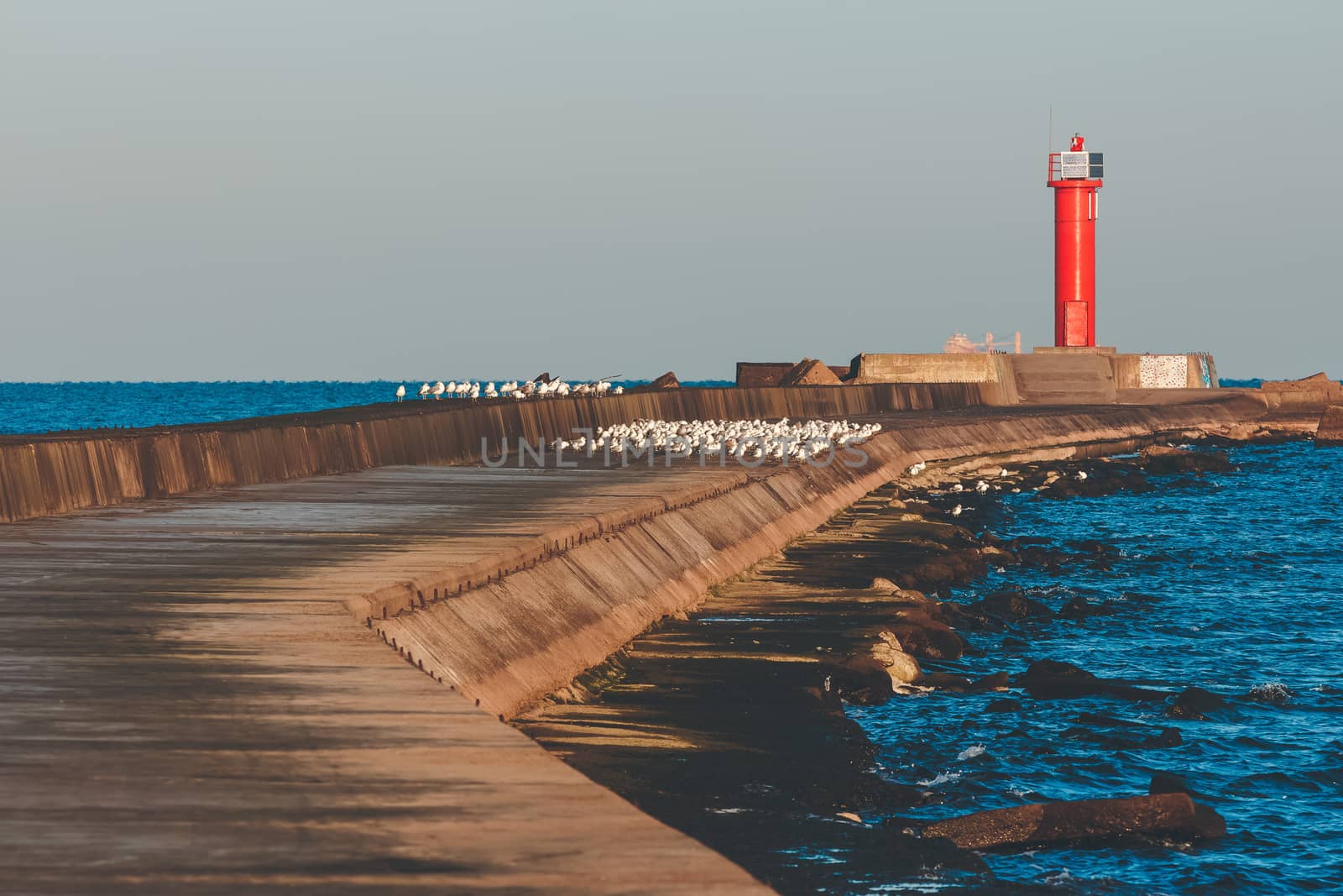 Red lighthouse on breakwater jetty at Baltic sea