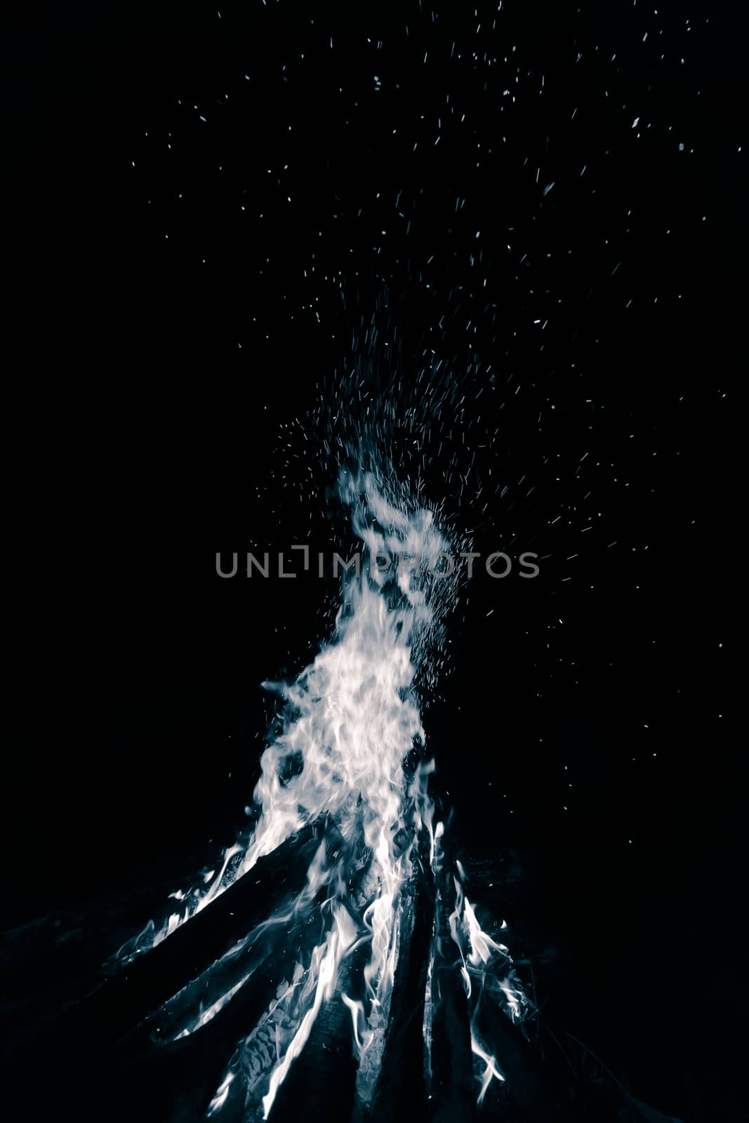 Blue bonfire with flying sparks isolated on black