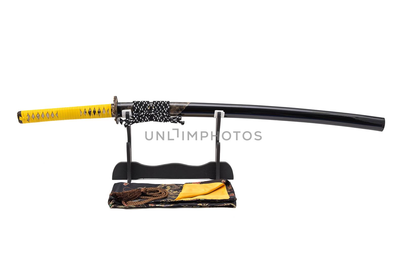 Japanese sword with yellow leather cord wrapped on handle and scabbard with ray skin on stand  white background, black silk bag at front.