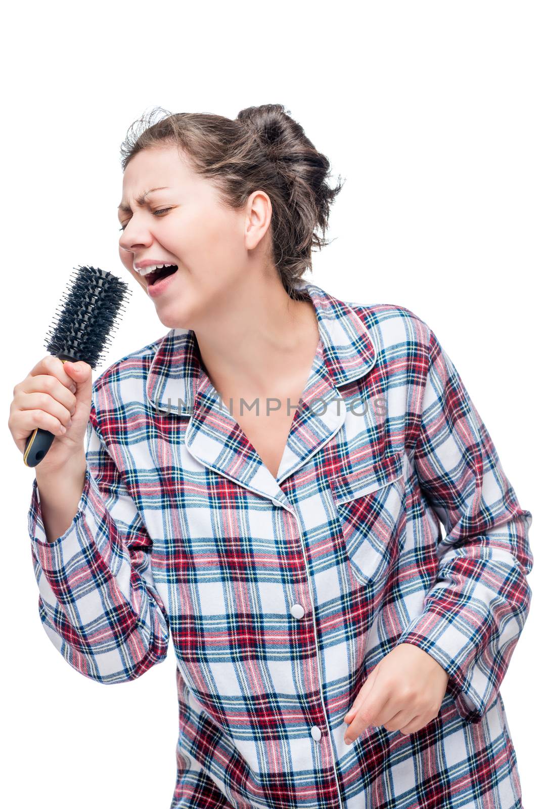 A girl in pajamas loves a song to sing, instead of a microphone a hairbrush on a white background