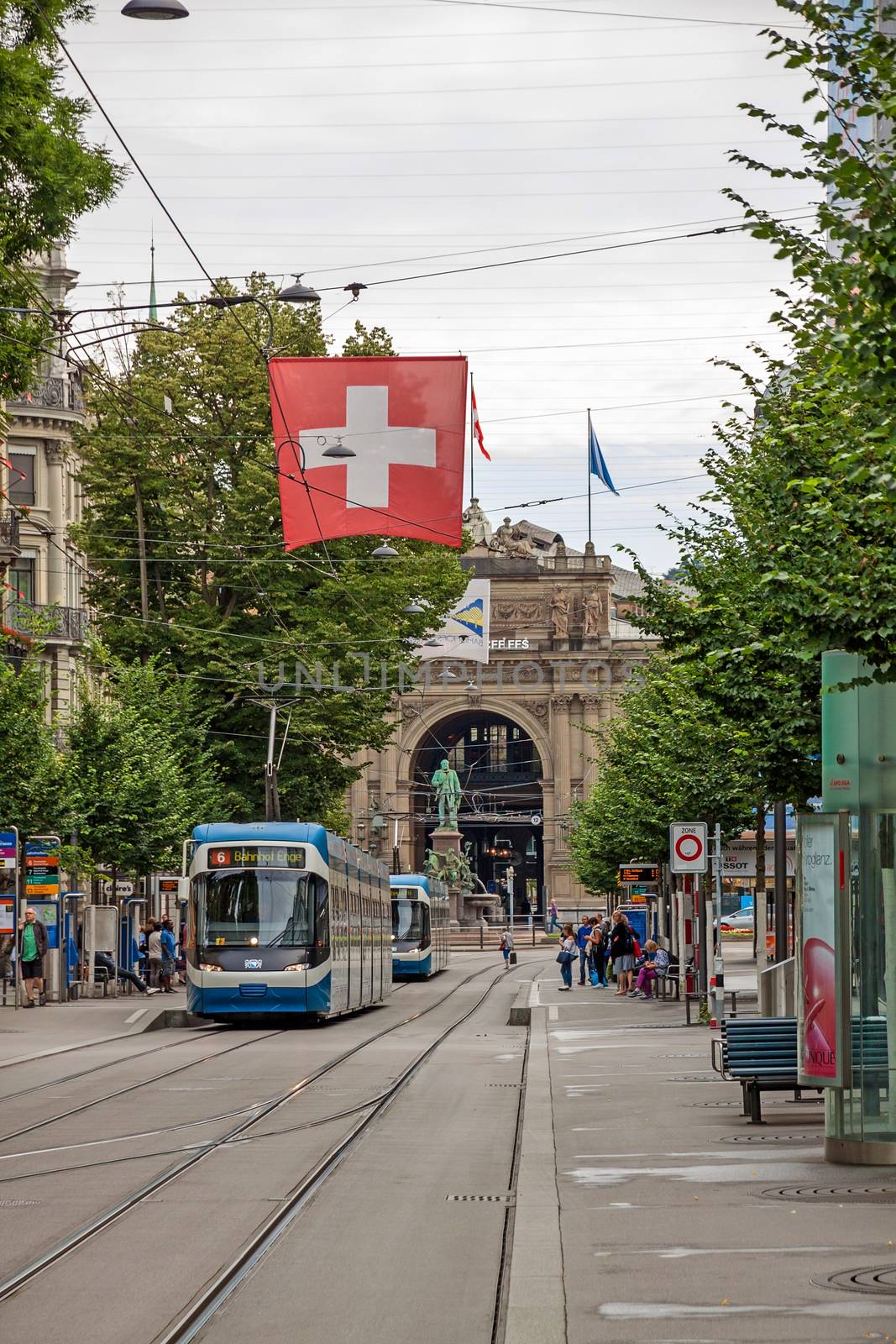 Zurich shopping street Bahnhofstrasse with tram and swiss flag by aldorado