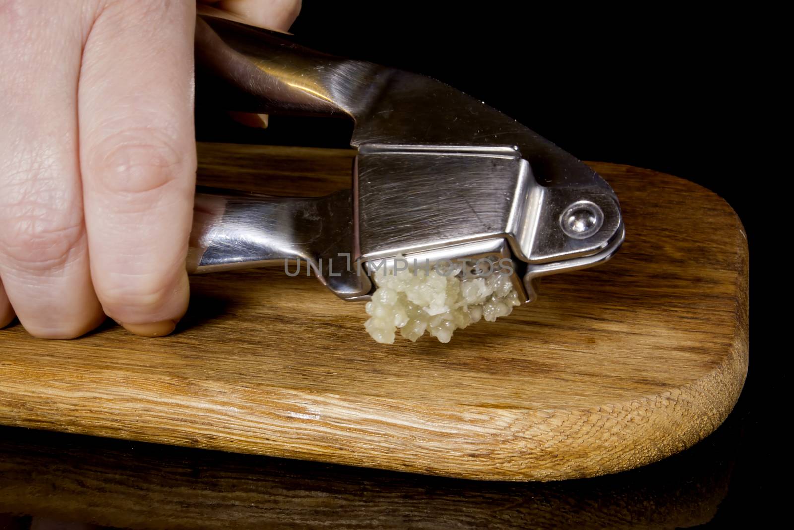 Garlic press and cloves of garlic laid on a wooden table background