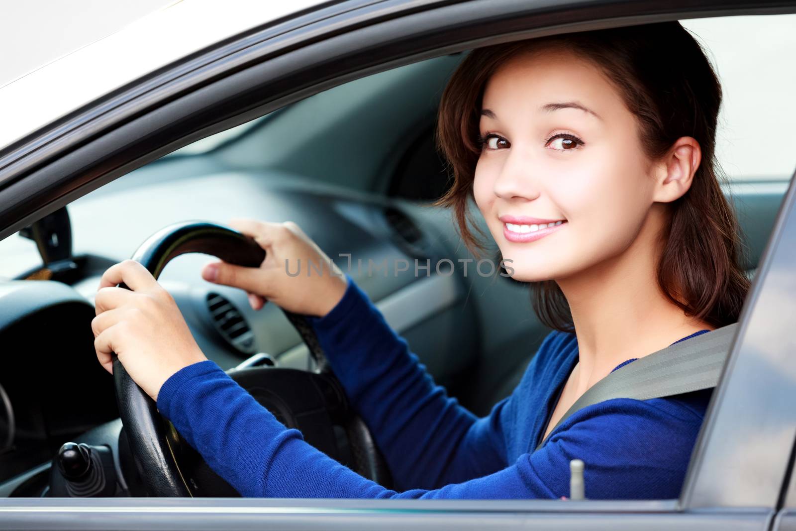 Beautiful woman driver smiling to you from her car