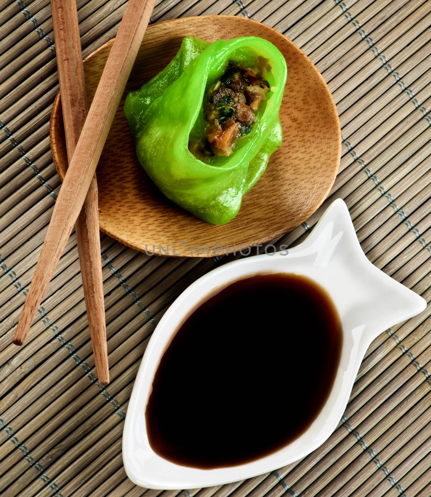 Vegetarian Yasai Dim Sum on Wooden Plate with Soy Sauce and Chopsticks closeup on Straw Mat background