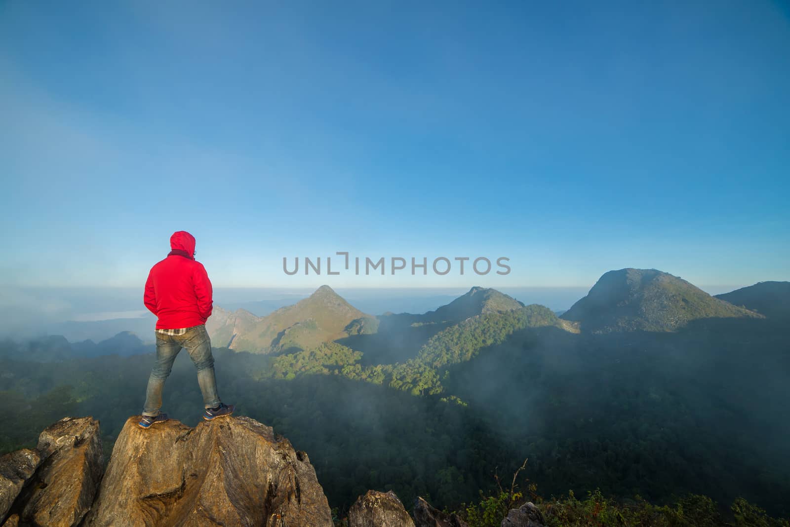 Man on top of mountain sitting on the rock watching a view landscape at Doi Luang Chiang Dao, ChiangMai Thailand.