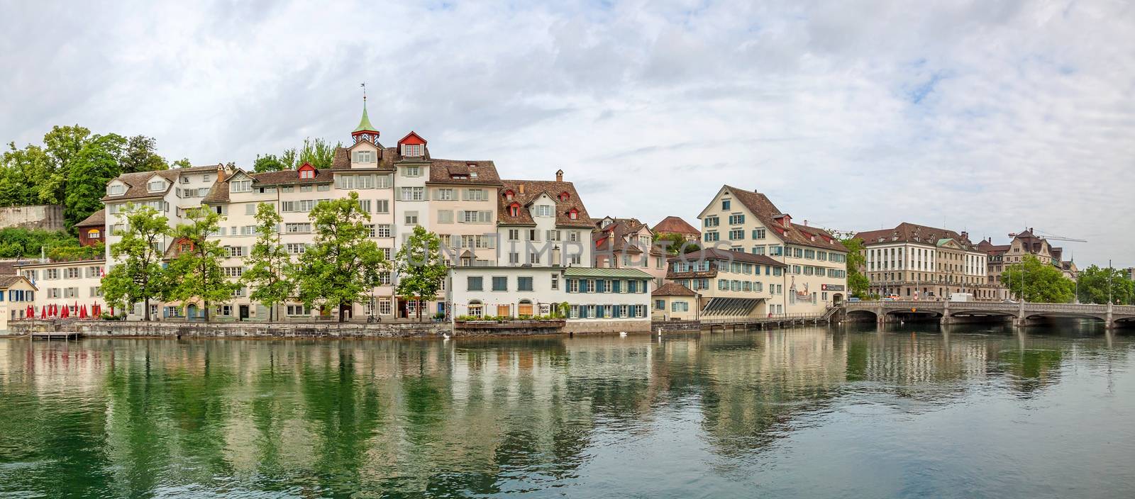 Zurich, Switzerland - June 10, 2017: Panorama of river Limmat, sight Taufergedenkplatte (left) and historic buildings riversides. View from Limmatquai.