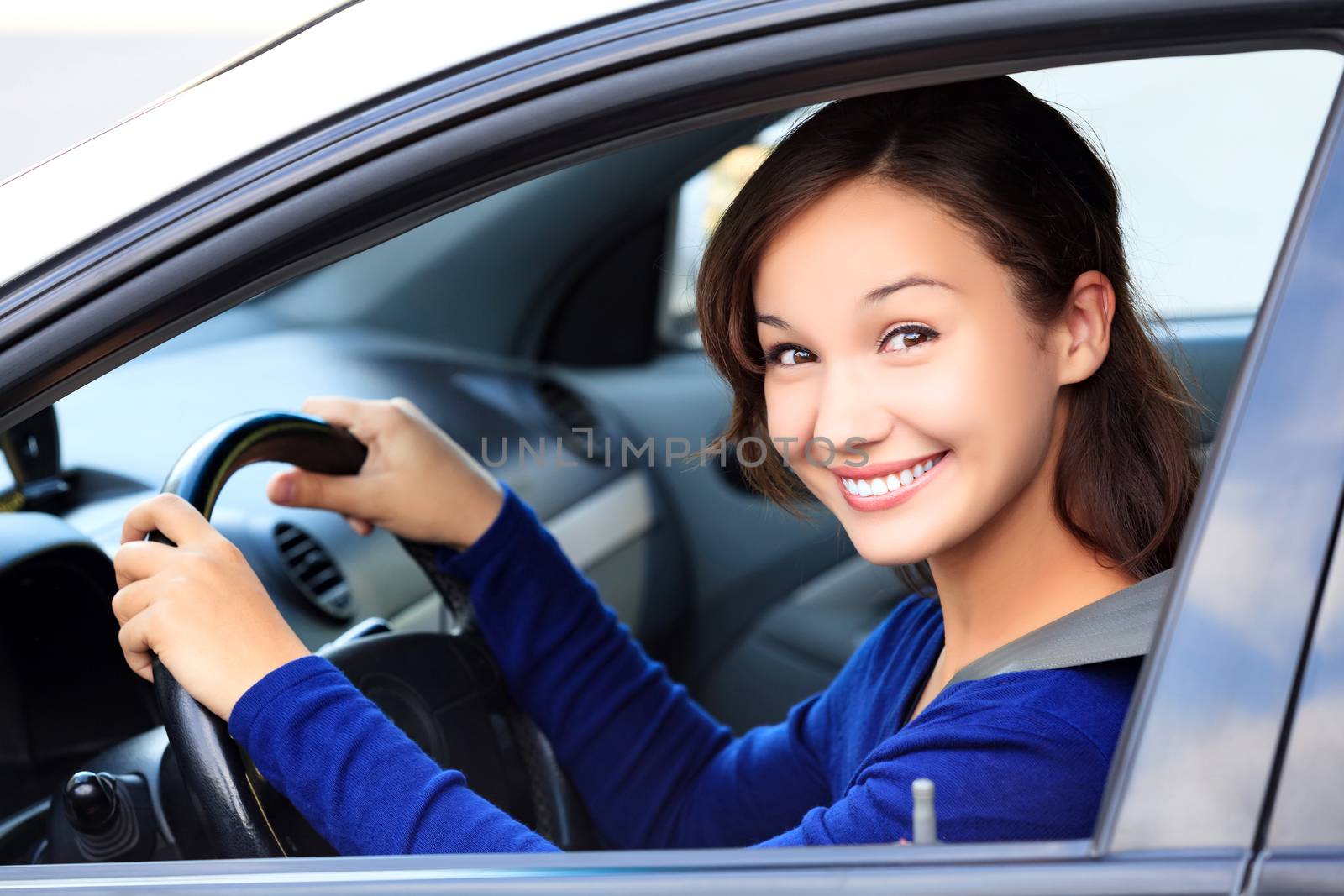 Beautiful woman driver smiling to you from her car by Nobilior