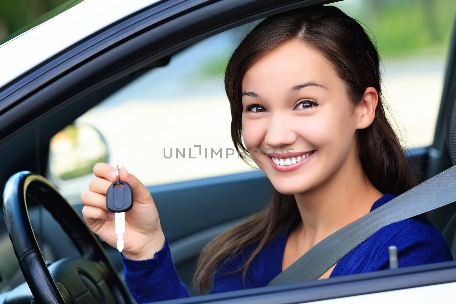 Beautiful young smiling happy girl shows the car key in her hand