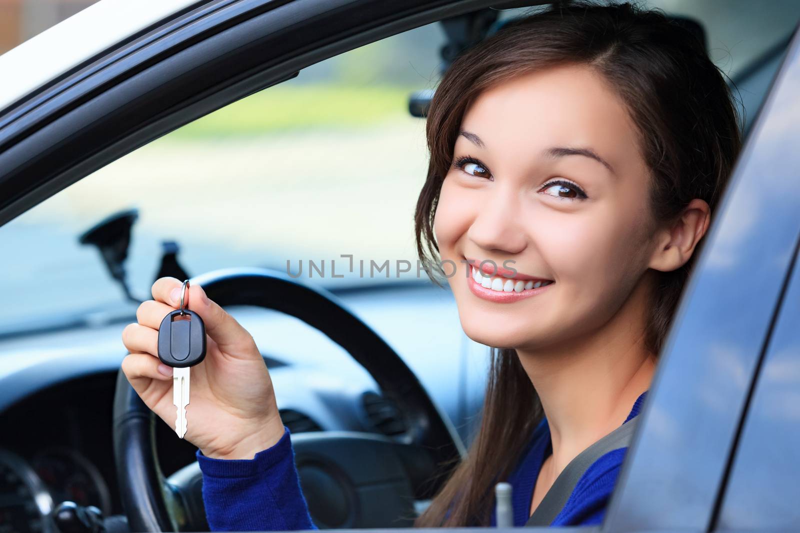 Beautiful young smiling happy girl shows the car key in her hand by Nobilior