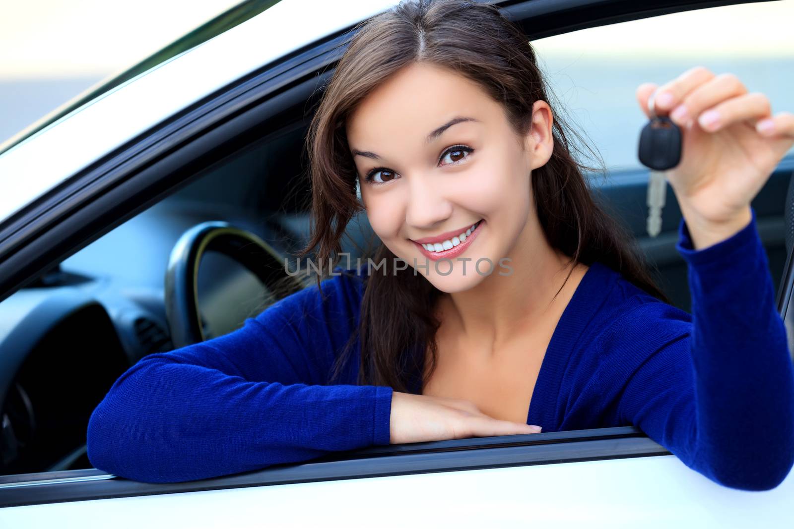 Beautiful young smiling happy girl shows the car key in her hand by Nobilior