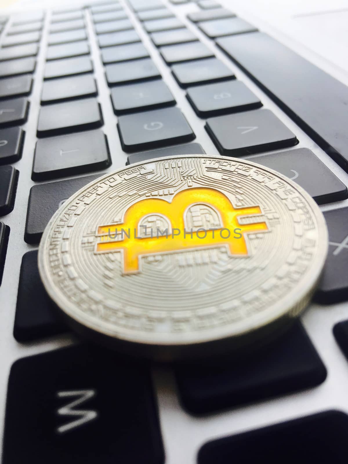 Cryptocurrency physical silver bitcoin coin on black computer keyboard.