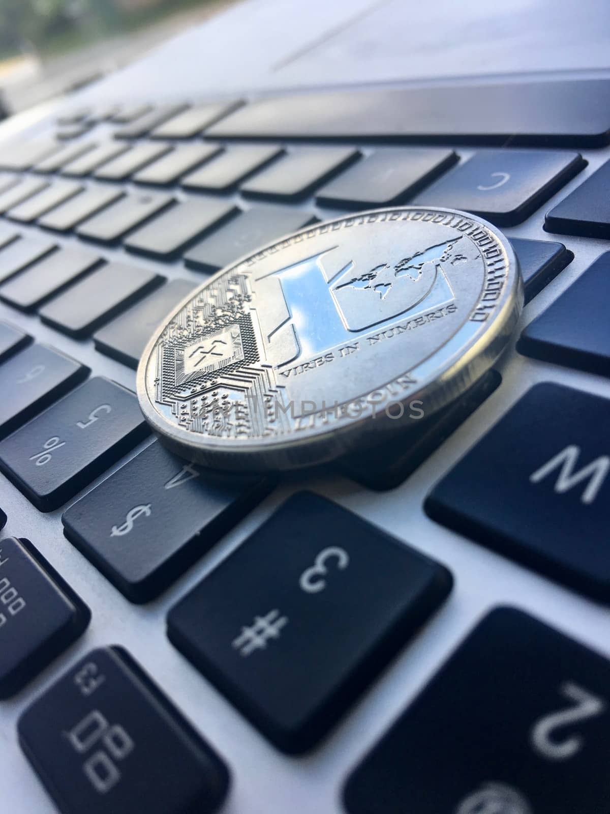 Cryptocurrency physical silver Litecoin coin on the computer keyboard.