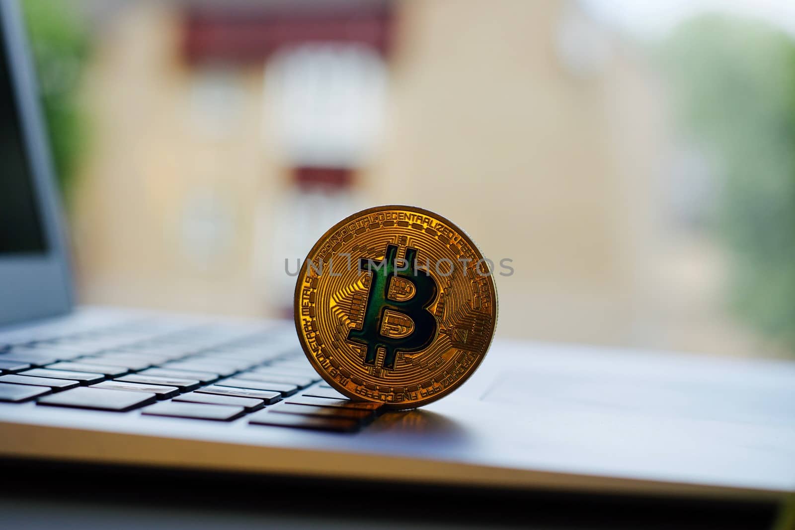 Cryptocurrency physical gold bitcoin coin on the computer keyboard near window.