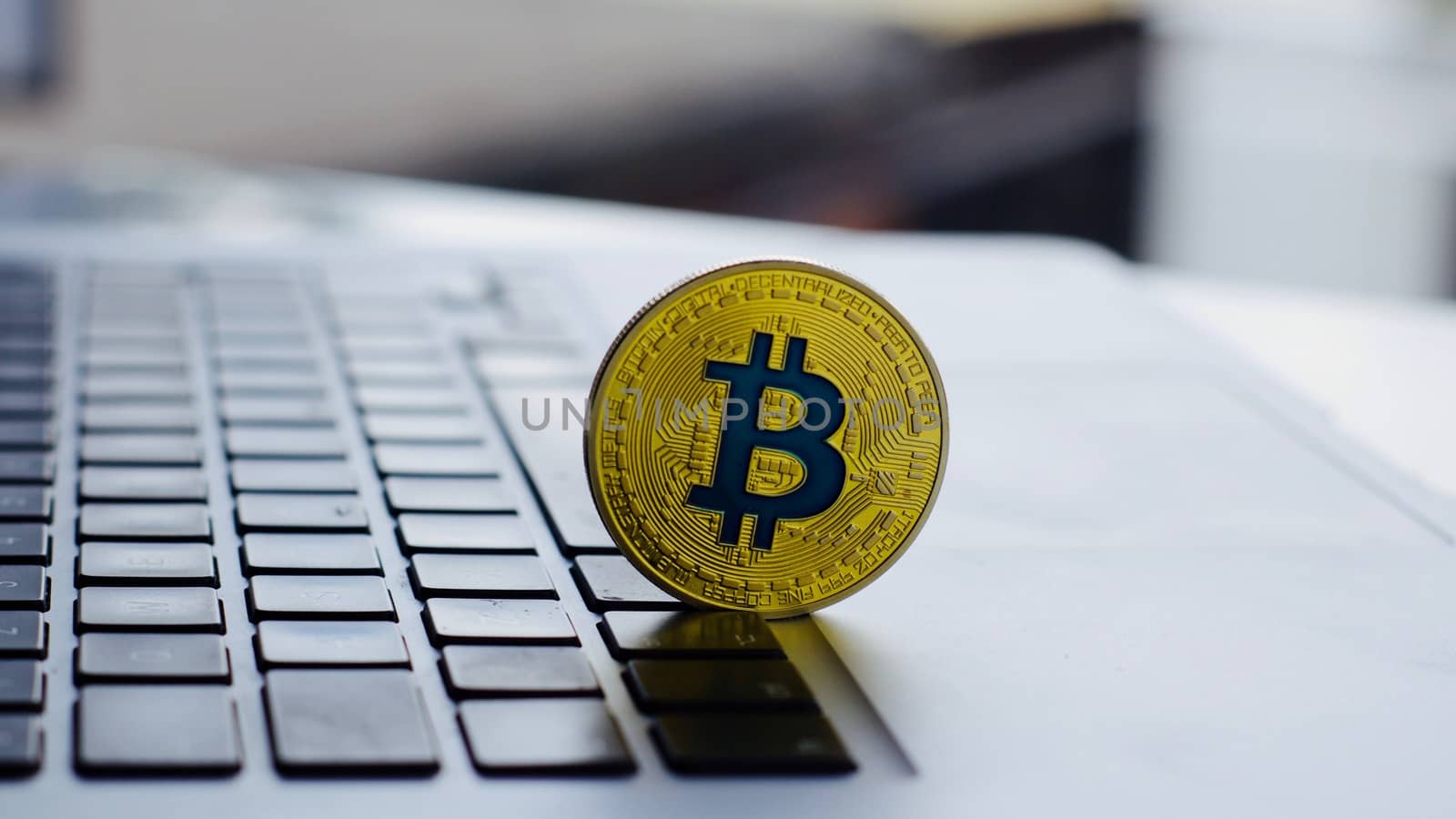 Cryptocurrency physical gold bitcoin coin with blue sign on the black computer keyboard.