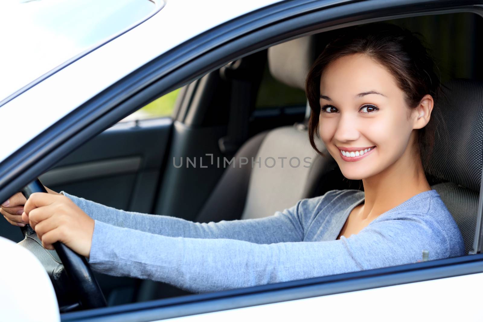 Beautiful woman driver smiling to you from her car