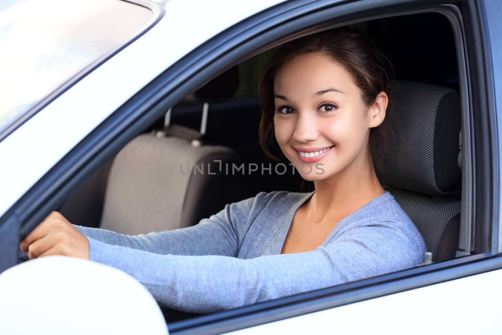 Beautiful woman driver smiling to you from her car