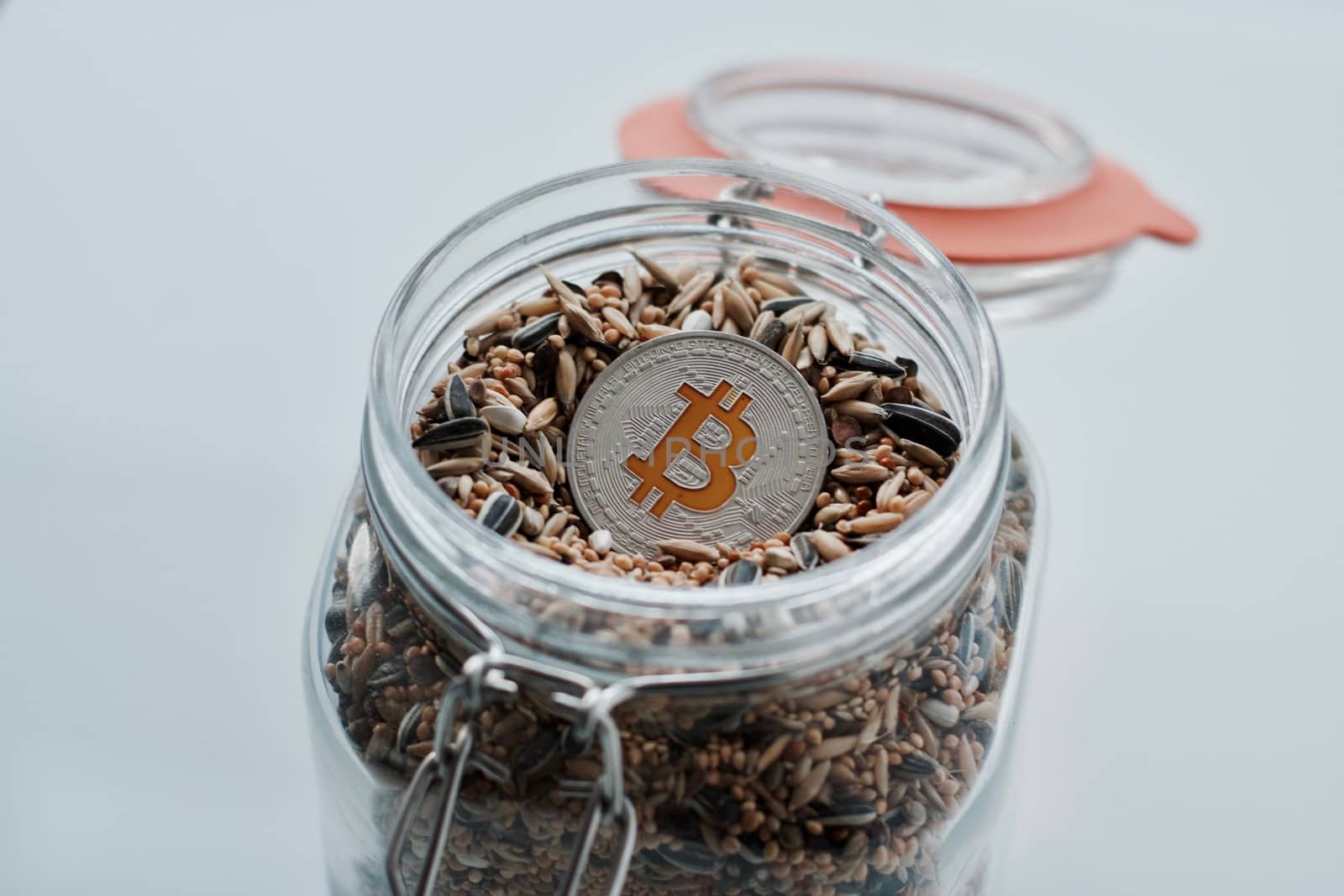 Cryptocurrency physical silver bitcoin coin in jar with seeds.