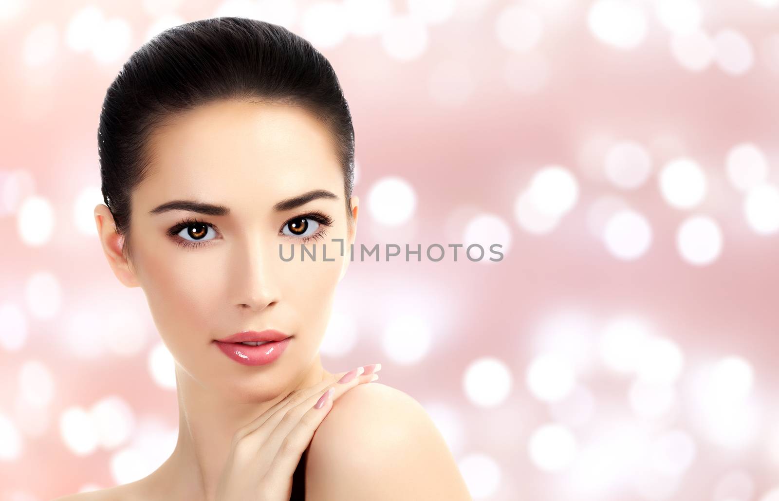 Closeup headshot portrait of a beautiful woman with beauty face and clean smooth soft skin, mild makeup. Abstract background with blurred lights