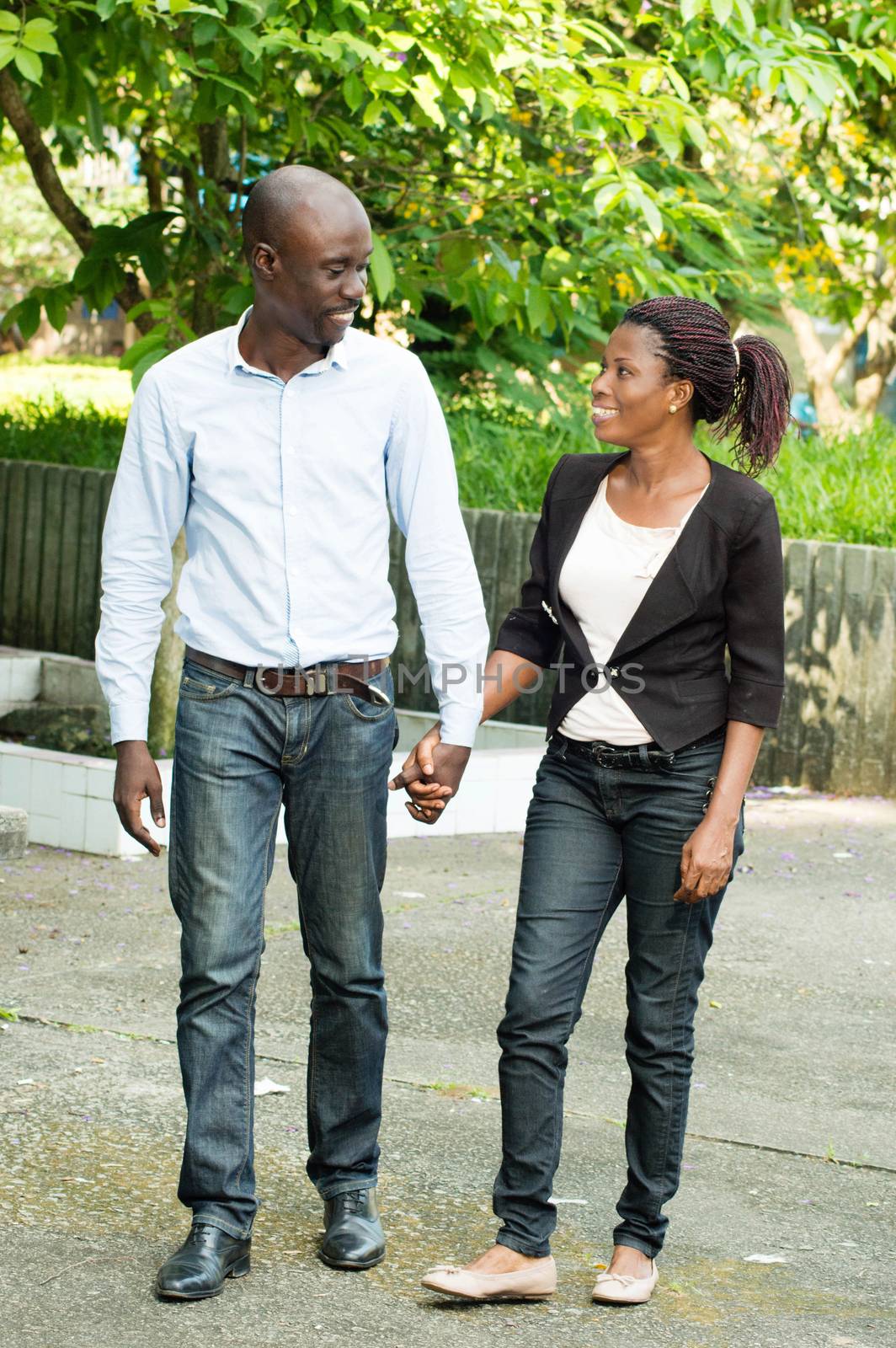 This couple , hand in hand stroll in a park.