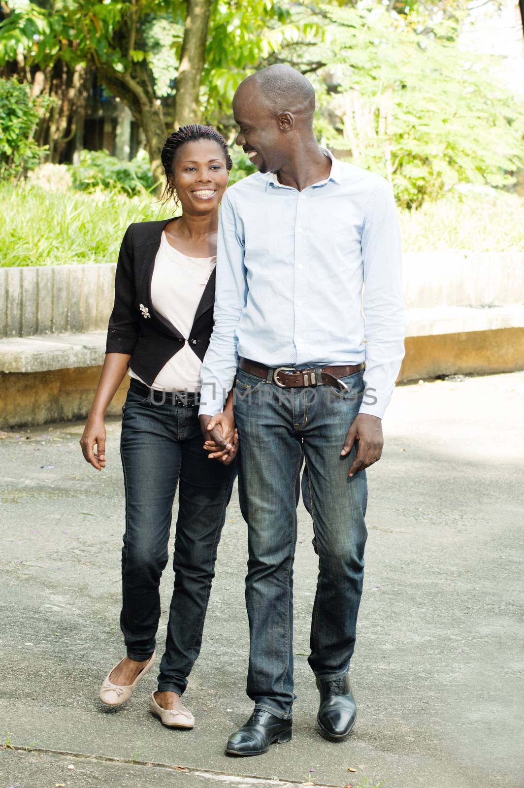 This couple , hand in hand stroll in a park.