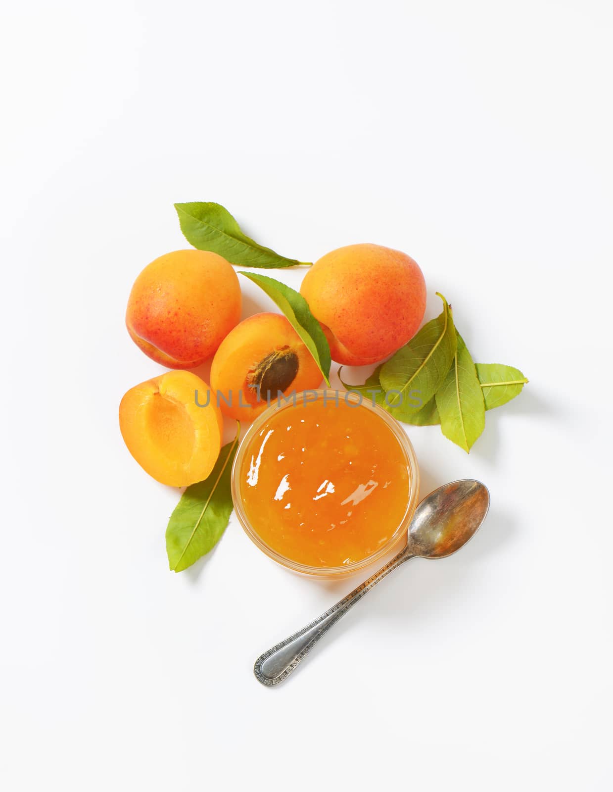 fresh apricots and bowl of apricot jam on white background