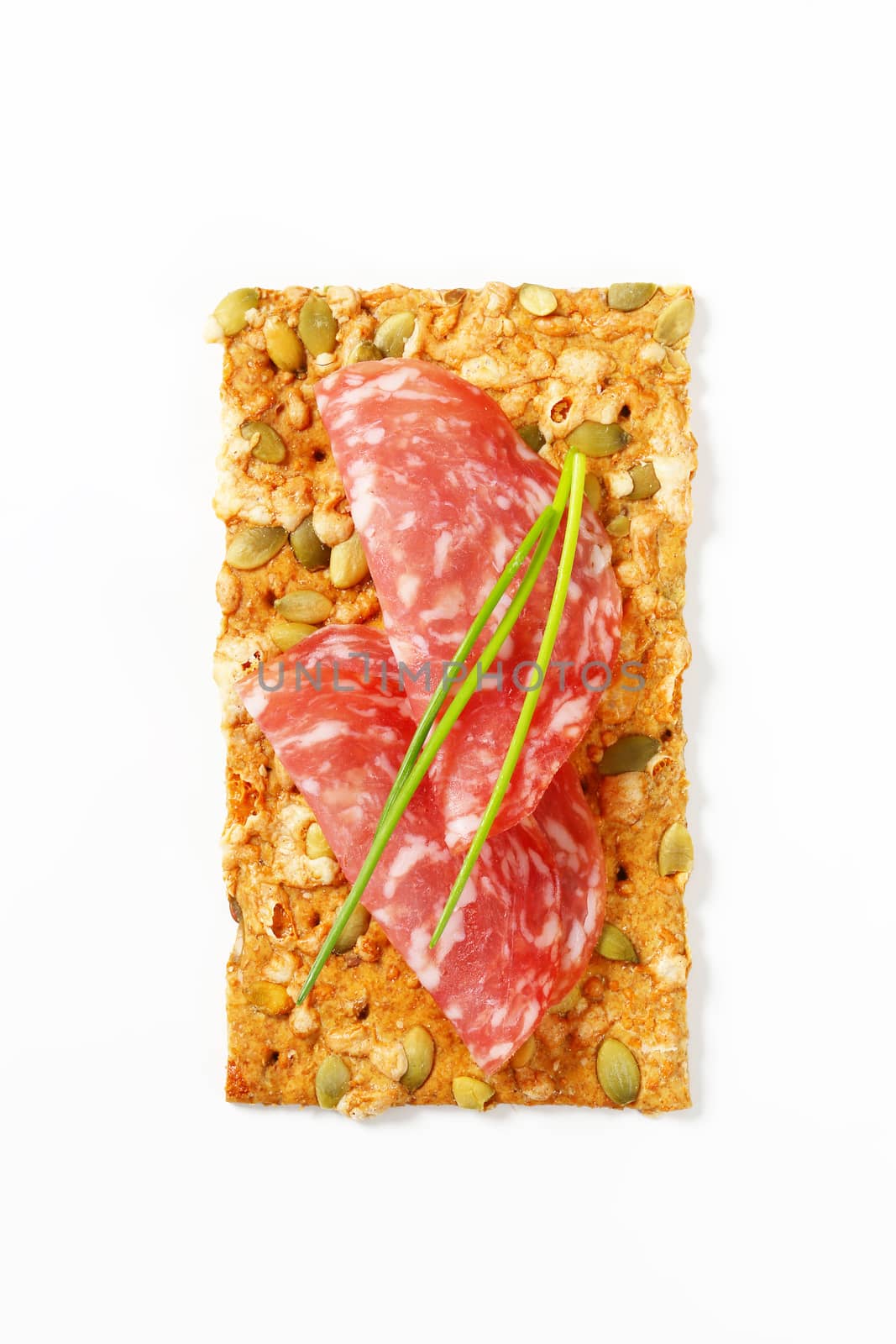 pumpkin seed cracker with thin slices of dry salami sausage