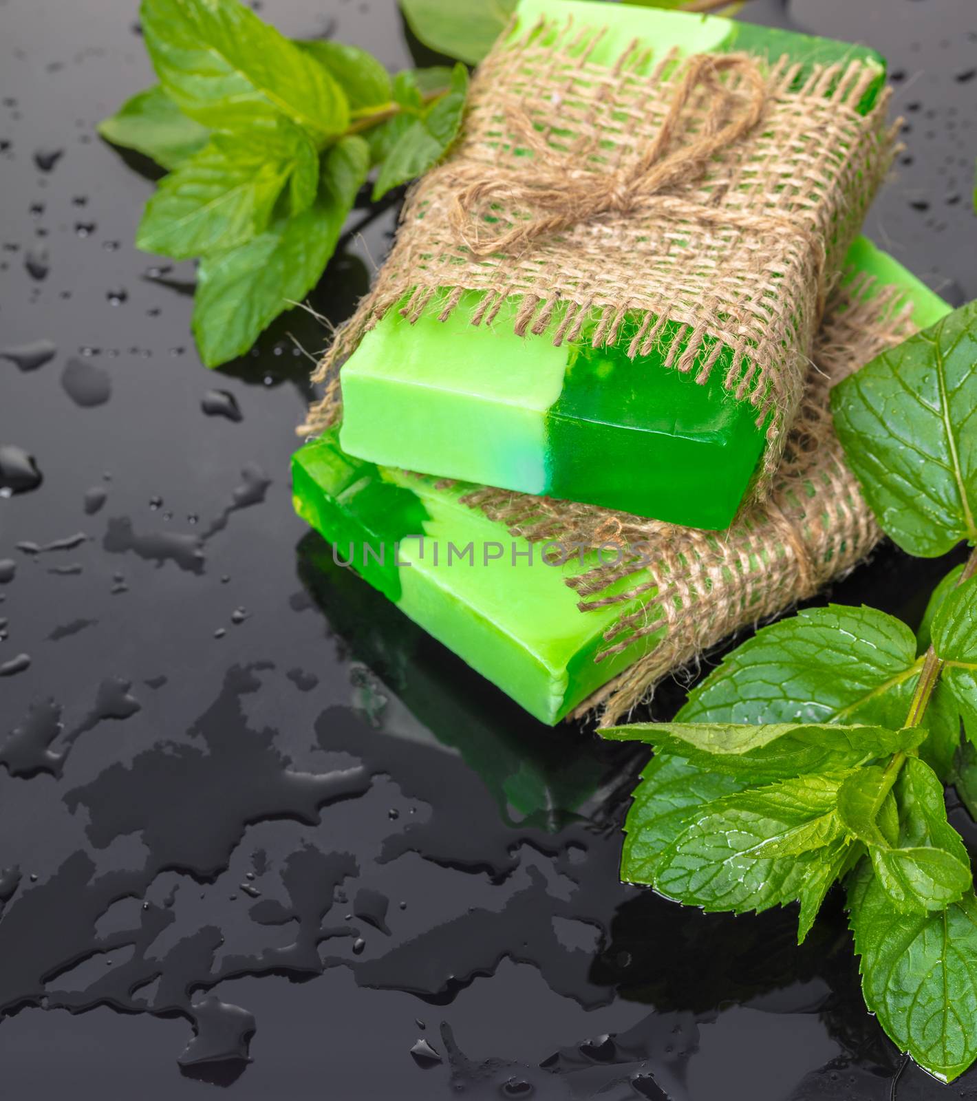 Handmade soap green with mint leaves on a black background and drops of water